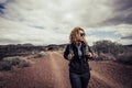 Beautiful trekker caucasian blonde curly young active woman walk in the desert path enjoying the freedom and the active lifestyle