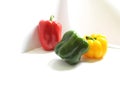 Beautiful triangular composition of fresh bell peppers in bright green, red and yellow colors on a white background with lighting