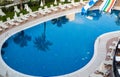 Beautiful tropical beach front hotel resort with swimming pool, sun-loungers and palm trees during a warm sunny morning Royalty Free Stock Photo