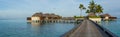 Beautiful tropical beach panorama of bungalos with bridge near the ocean with palms trees at Maldives Royalty Free Stock Photo