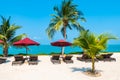 Beautiful tropical beach sea ocean with umbrella and chair around coconut palm tree on blue sky Royalty Free Stock Photo