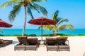 Beautiful tropical beach sea ocean with umbrella and chair around coconut palm tree on blue sky Royalty Free Stock Photo