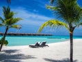 Beautiful tropical island nature, two sun beds, loungers, under palm tree leaves. White sand, sea view horizon, idyllic blue sky, Royalty Free Stock Photo