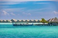 Beautiful tropical Maldives beach under cloudy sky with dhoni boat and water villas, bungalows. Luxury vacation Royalty Free Stock Photo