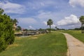 Beautiful tropical nature landscape. Stone path between pond and golf field on blue sky with white clouds background. Royalty Free Stock Photo