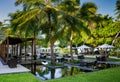 Beautiful tropical outdoors restaurant setup with tables in water surrounded by palm trees at Maldives