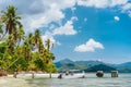 Beautiful tropical scenery beach with palm trees, jetty pier, tourist boat and white clouds above. Holiday and paradise island