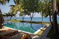 Beautiful tropical swimming pool in hotel or resort with umbrella, coconuts tree sun-loungers in Bali Royalty Free Stock Photo