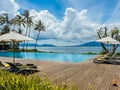 Beautiful tropical swimming pool in hotel or resort with umbrella, coconuts tree sun-loungers, palm trees with infinity pool view Royalty Free Stock Photo