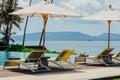 Beautiful tropical swimming pool in hotel or resort with umbrella, coconuts tree sun-loungers, palm trees with infinity pool view Royalty Free Stock Photo