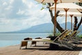 Beautiful tropical swimming pool in hotel or resort with umbrella, coconuts tree sun-loungers, palm trees with infinity pool view Royalty Free Stock Photo