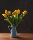 beautiful tulips in a blue vase on a dark wooden table on a dark background Royalty Free Stock Photo