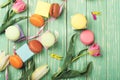 Beautiful tulips with colorful macaroons on greenery wooden back