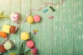 Beautiful tulips with colorful macaroons on greenery wooden back