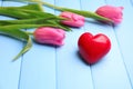 Beautiful tulips and red heart on color wooden background Royalty Free Stock Photo