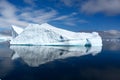 Beautiful turquoise iceberg with texture and cave on beautiful day in Antarctica reflecting in calm water Royalty Free Stock Photo