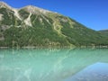 Beautiful turquoise Kucherla lake. Reflection of mountains in the water. Summer vacation in the mountains. Arrow image formed by