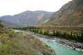 A beautiful turquoise river flows through a picturesque autumn valley surrounded by high mountain ranges Royalty Free Stock Photo