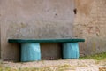 Beautiful turquoise simple wooden bench near an old building wall Royalty Free Stock Photo