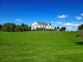 beautiful two story country home with a large manicured lawn and trees in the front yard. Blue sky and clouds Royalty Free Stock Photo