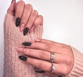 Beautiful two-tone manicure with gold design. Hands in a sweater with black and camouflage gel polish. Royalty Free Stock Photo