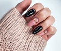 Beautiful two-tone manicure with gold design. Hands in a sweater with black and camouflage gel polish. Royalty Free Stock Photo