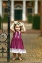 Beautiful two year old girl with a flower floral crown and a purple dress outside near an iron gate Royalty Free Stock Photo