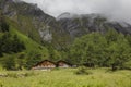 Beautiful Tyrolean houses surrounded by rocky mountains in the fog in Austrian Alps near the Grossglockner rock summit, Kals am Royalty Free Stock Photo