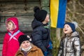 Beautiful Ukrainian children or kids with grandmother near a wooden house with flag of Ukraine