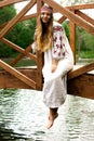Steep slender Ukrainian woman resting sitting on a wooden decorative bridge over the water on a hot sunny day