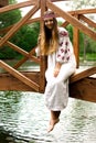 Steep slender Ukrainian woman resting sitting on a wooden decorative bridge over the water on a hot sunny day