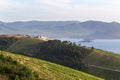 Beautiful undulating landscape with vineyards and a white house in the background of the sea and mountains