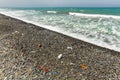 Beautiful unspoiled dark pebble stones beach with garbage, mostly plastic, washed out. Ocean littering concept