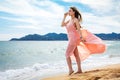 Beautiful unusual woman walking on the beach and posing in red d