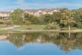 Beautiful urban park with lake reflection and apartment complex in background near Dallas