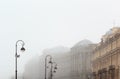 Brutal architecture with columns, stucco and rhythm of windows and lamp posts in foggy day.