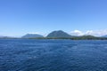 A beautiful vast full view blue seascape ocean photo with forested mountains in the background on a beautiful summer day