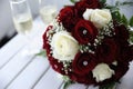 Beautiful velvety red and white roses wedding bouquet on a table with two champagne flutes aside Royalty Free Stock Photo