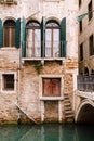 Close-ups of building facades in Venice, Italy. Beautiful Venetian windows with open wooden green shutters. An old red Royalty Free Stock Photo