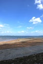 Beautiful vertical panorama landscape view of an empty yellow sand beach in shadow, turquoise ocean water, light blue sky, white Royalty Free Stock Photo