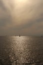 Beautiful vertical split at the horizon contrasty panorama day shot of small lonely boats in calm ocean under soft cloudy sky and