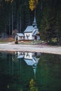 Little chapel reflecting in Lago di Braies in fall, Dolomites, South Tyrol, Italy