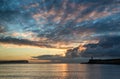 Beautiful vibrant sunrise sky over calm water ocean with lighthouse and harbor wall Royalty Free Stock Photo