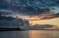 Beautiful vibrant sunrise sky over calm water ocean with lighthouse and harbor wall Royalty Free Stock Photo