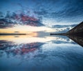 Beautiful vibrant sunrise sky over calm water ocean with lighthouse and harbor wall Royalty Free Stock Photo