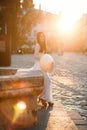 Beautiful Vietnamese girl dressed in traditional white Ao Dai dress stands near the fountain at the background of