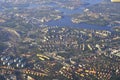 Beautiful view from airplane window looking down on blue water, town, roads, houses and buildings. City urban area with bright