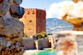 Beautiful view of ancient Red Tower in Alanya, Turkey, between two merlons of old stone wall. Sandy beach under old historic walls Royalty Free Stock Photo