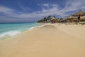 Beautiful view of Atlantic ocean with people lying on sun loungers under sun umbrellas on sandy Eagle beach.