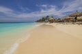 Beautiful view of Atlantic ocean with people lying on sun loungers under sun umbrellas on sandy Eagle beach. Aruba.